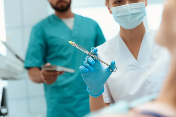 Vrouwelijke en mannelijke tandartsen behandelen een meisje in een tandheelkundige stoel zit — Stockfoto