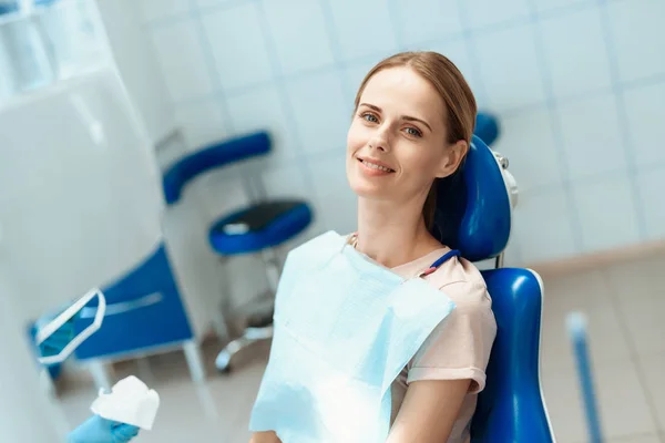 Mulher posando em cadeira dental azul e sorrindo — Fotografia de Stock