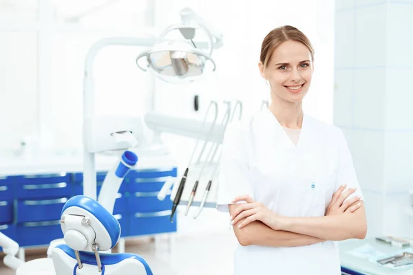 Dentista posando contra um fundo de equipamentos odontológicos em uma clínica odontológica. Ela sorri. — Fotografia de Stock