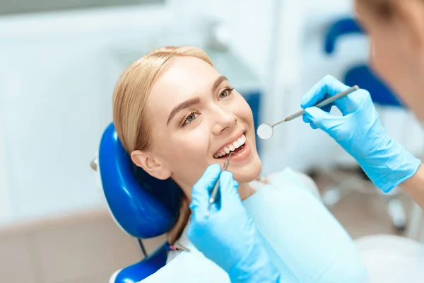 Kvinnan kom till tandkliniken. Hon sitter i dentala stol och ler — Stockfoto