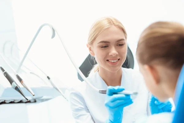 Une petite fille à une réception avec un dentiste. Médecin féminin se préparant à examiner les dents d'une fille — Photo