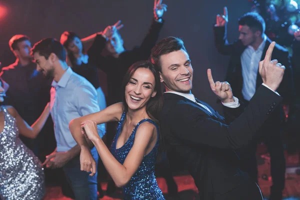 Ludzie bawić się w nowy rok party. Na pierwszym planie tańczą facet i dziewczyna. — Zdjęcie stockowe