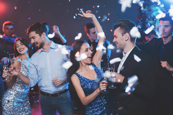 Young people have fun at a New Year's party. In the foreground two pairs dance.
