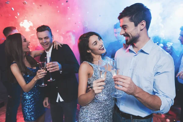 Los jóvenes se divierten en una fiesta de Año Nuevo. En primer plano, una pareja está bailando con gafas en sus manos . — Foto de Stock