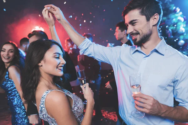 Young people have fun at a New Year's party. In the foreground, a couple is dancing with glasses in their hands. — Stock Photo, Image