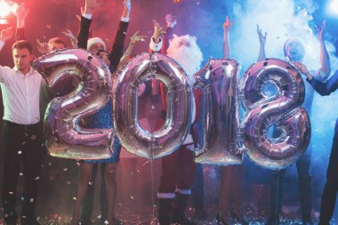 Gençlerin yeni yıl partisinde büyük parlak Ulusal teketim numaraları 2018 şeklinde ile poz olan. Çocuklar eğleniyor musun. Arkalarında çok renkli bir sis olduğunu.