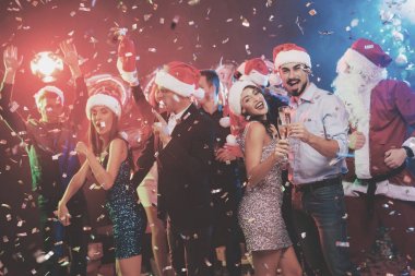 Genç çift bardak şampanya elinde dans. Onların arkasında onların arkadaşları ve Noel Baba gibi giyinmiş adam dans.