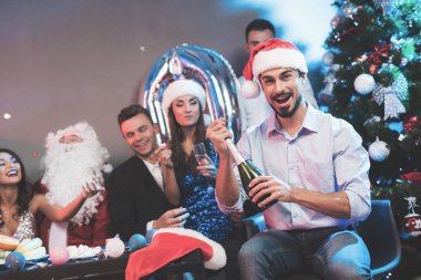 Noel Baba şapkalı bir adam bir şişe şampanya açar. Bir erkek arkadaş oturup onu ve bir adam yanında Noel Baba gibi giyinmiş