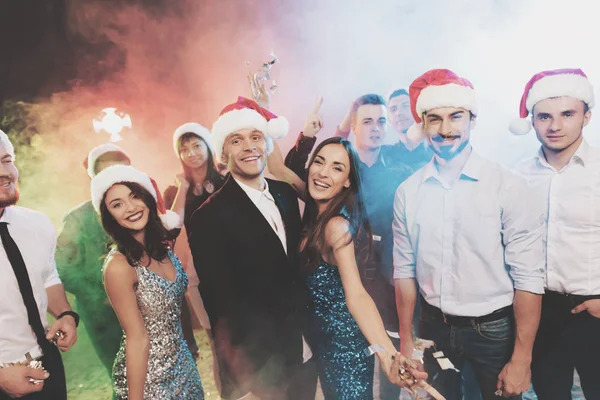 Jugendliche haben Spaß bei einer Silvesterparty. die Jungs setzen Weihnachtsmann-Hüte auf. — Stockfoto