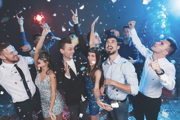 Young people have fun at a New Year's party. Around them flies confetti.