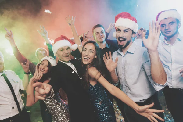 Jugendliche haben Spaß bei einer Silvesterparty. die Jungs setzen Weihnachtsmann-Hüte auf. — Stockfoto