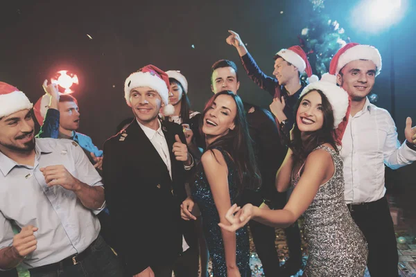 Young people have fun at a New Year\'s party. The guys put on Santa Claus hats.