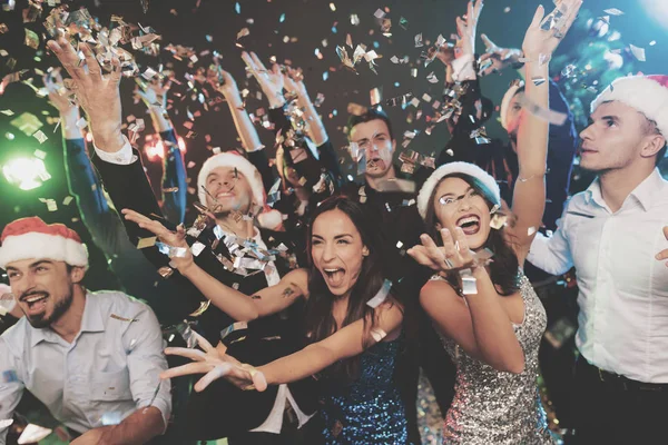 Jonge mensen hebben plezier op een New Year's party. Om hen heen vliegt confetti. — Stockfoto