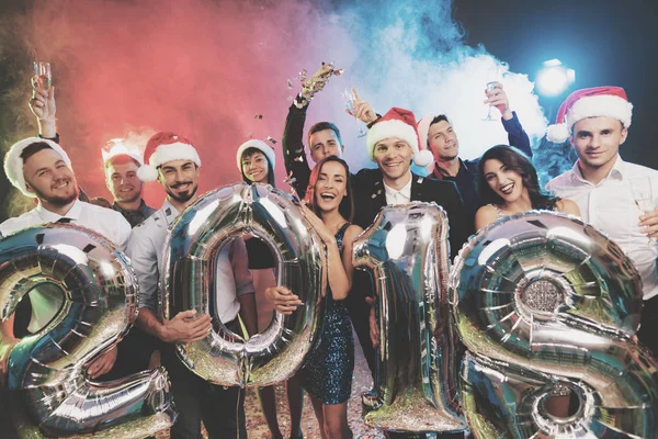 Die jungen Leute auf der Silvesterparty posieren mit glänzenden Zahlen im Jahr 2018. die Jungs haben Spaß. — Stockfoto