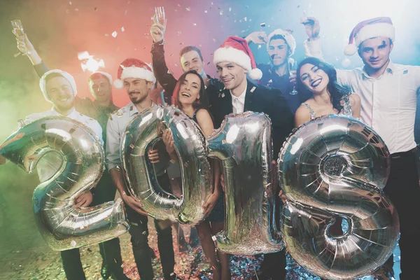 Os jovens na festa de Ano Novo estão posando com números brilhantes em 2018. Os rapazes estão a divertir-se. . — Fotografia de Stock