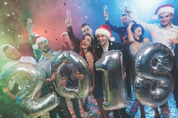 Los jóvenes en la fiesta de Año Nuevo están posando con figuras brillantes en 2018. Los chicos se están divirtiendo. . —  Fotos de Stock