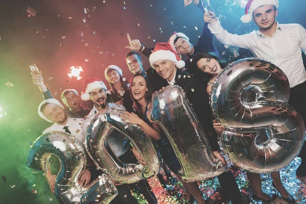 Os jovens na festa de Ano Novo estão posando com números brilhantes em 2018. Os rapazes estão a divertir-se. . — Fotografia de Stock