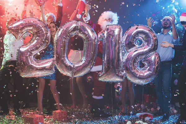 Os jovens na festa de Ano Novo estão posando com grandes bolas infláveis brilhantes na forma de números 2018 . — Fotografia de Stock