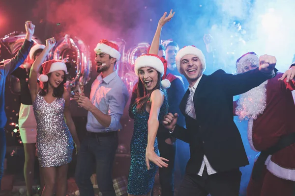 Young couple having fun at New Year's party. They dance in santa claus caps. — Stock Photo, Image