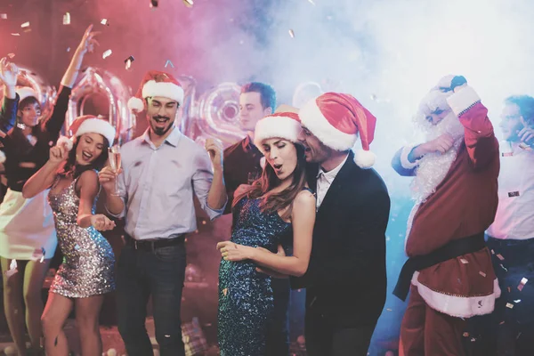 Pareja joven divirtiéndose en la fiesta de Año Nuevo. Bailan en gorras de Santa Claus. . — Foto de Stock