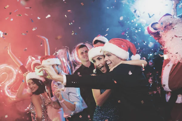 Casal jovem se divertindo na festa de Ano Novo. Eles fazem selfie em um smartphone . — Fotografia de Stock