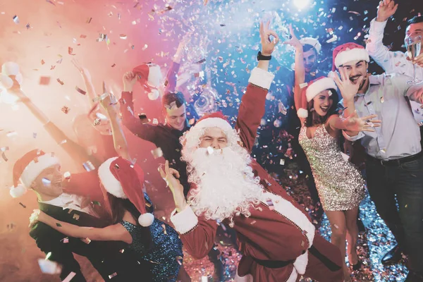 Ein als Weihnachtsmann verkleideter Mann amüsiert sich auf einer Silvesterparty. zusammen mit ihm Spaß haben Freunde. — Stockfoto