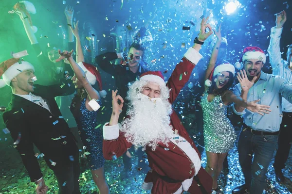 Um homem vestido de Papai Noel se diverte em uma festa de Ano Novo. Juntamente com ele ter amigos divertidos . — Fotografia de Stock