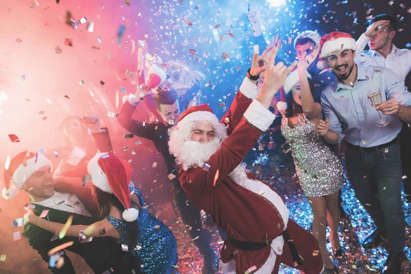 Um homem vestido de Papai Noel se diverte em uma festa de Ano Novo. Juntamente com ele ter amigos divertidos . — Fotografia de Stock