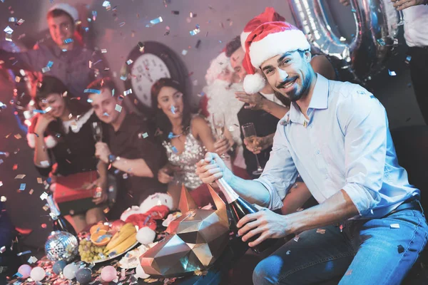 Ein Mann Mit Weihnachtsmannmütze Öffnet Eine Flasche Champagner Neben Ihm — Stockfoto