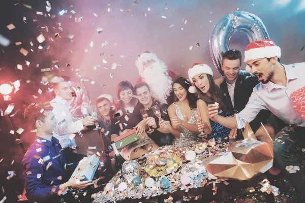 Feliz compañía en la fiesta de Año Nuevo. La gente bebe champán e intercambian regalos. . —  Fotos de Stock