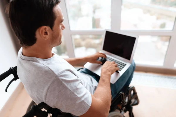 De gehandicapte persoon zit in een rolstoel voor een groot panoramisch raam. — Stockfoto