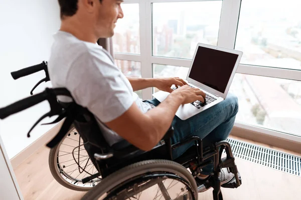 De gehandicapte persoon zit in een rolstoel voor een groot panoramisch raam. — Stockfoto