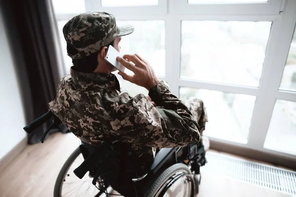 Niepełnosprawnych w mundur siedzi w wózku inwalidzkim duże panoramiczne okna. — Zdjęcie stockowe