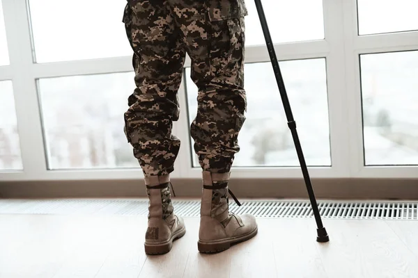 Fecha. Um soldado deficiente está encostado a uma muleta junto à janela. Ele olha para a grande janela panorâmica . — Fotografia de Stock