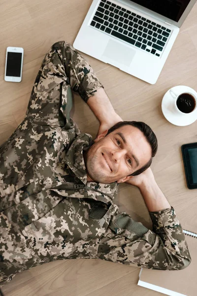 Un homme en uniforme est allongé sur une table entourée de gadgets modernes . — Photo