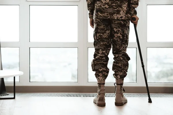 Близько. Солдат з обмеженими можливостями спирається на череп біля вікна. Він дивиться у велике панорамне вікно . — стокове фото