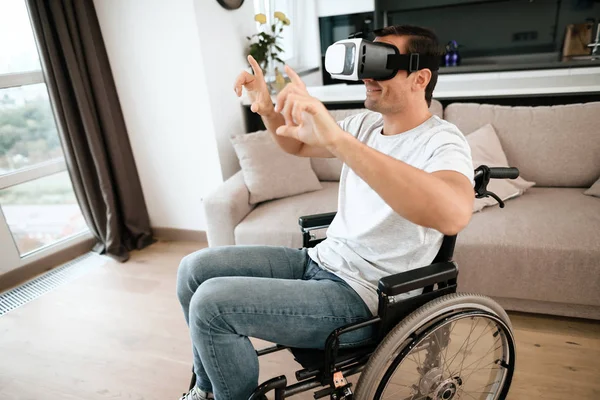 La persona con discapacidad está sentada en una silla de ruedas con gafas de realidad virtual. Extendió sus manos a los lados. . —  Fotos de Stock