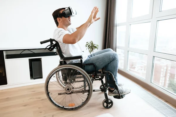 La persona con discapacidad está sentada en una silla de ruedas con gafas de realidad virtual. Extendió sus manos a los lados. . —  Fotos de Stock