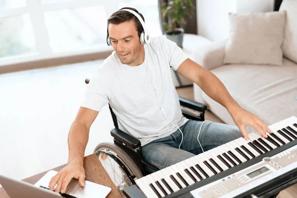 The disabled person is sitting in a wheelchair in front of the synthesizer. He plays music. — Stock Photo, Image