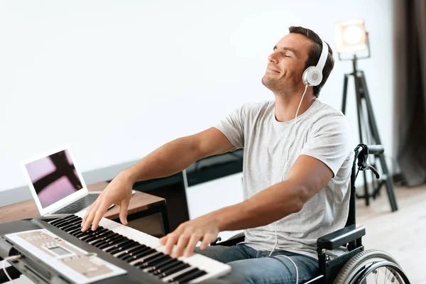 De gehandicapte persoon zit in een rolstoel voor de synthesizer. Hij speelt muziek. — Stockfoto