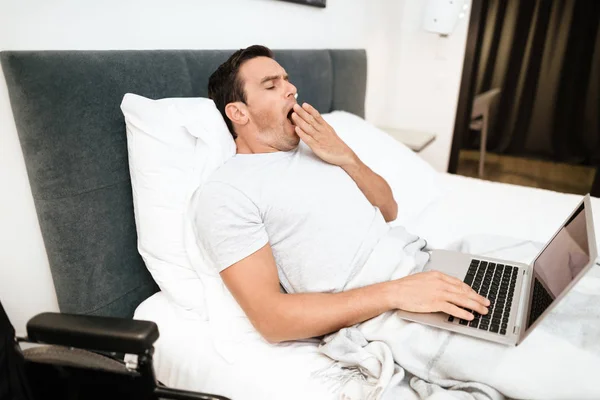 Los discapacitados están acostados en la cama y trabajando con un ordenador portátil. Se acaba de despertar. . —  Fotos de Stock