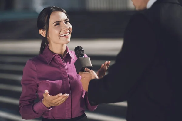 Egy nő arcán mosollyal válaszol a kérdésre. Egy ember tart egy mikrofon, hallgató-hoz választ — Stock Fotó