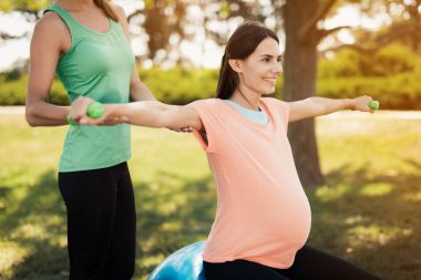 Gebelik yoga. Bir koç bir top için yoga egzersizleri hamile bir kadına yardımcı olur.