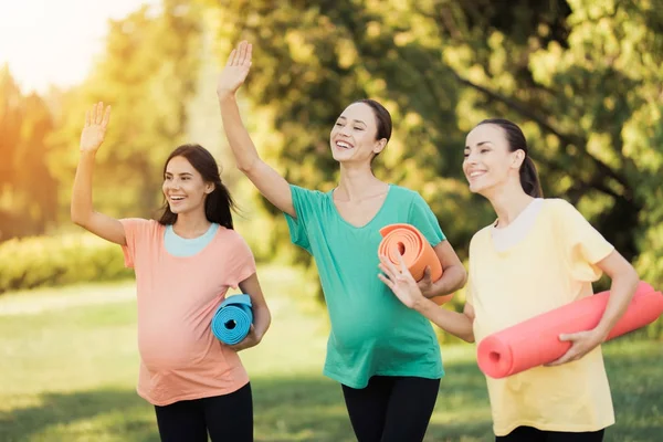 Три вагітні дівчата позують у парку з килимками для йоги. Вони посміхаються і розважаються — стокове фото
