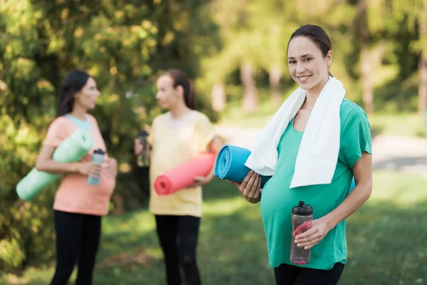 Drei schwangere Mädchen kamen zum Fitnesstraining in den Park. ein Mädchen im grünen T-Shirt posiert mit einer Sportflasche — Stockfoto