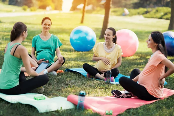 Беременная йога. Женщина-тренер сидит перед тремя беременными женщинами, которые пришли на йогу — стоковое фото