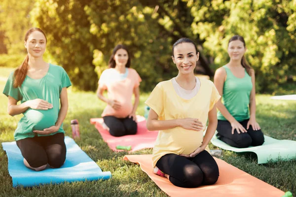 Yoga del embarazo. Tres mujeres embarazadas haciendo ejercicios de yoga en el parque — Foto de Stock