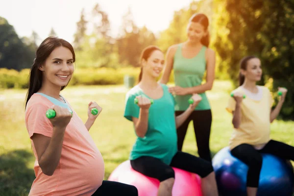 Ioga de gravidez. Três mulheres grávidas estão envolvidas em fitness no parque. Sentam-se em bolas para ioga — Fotografia de Stock