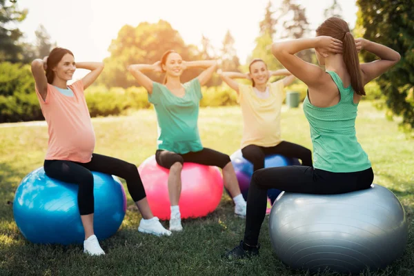 Ioga de gravidez. Três mulheres grávidas em ioga no parque. Fazem os exercícios com o treinador. — Fotografia de Stock