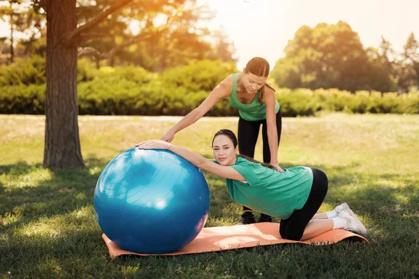 Schwangerschaftsyoga. Eine Frau macht Übungen auf einem blauen Ball für Yoga. Der Trainer hilft ihr — Stockfoto